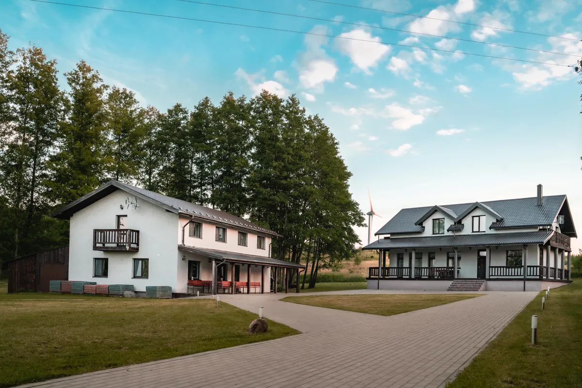 The two villas side by side — Deluxe Villa and The Villa connected by a garden path at golden hour, lake in background, festive outdoor lighting