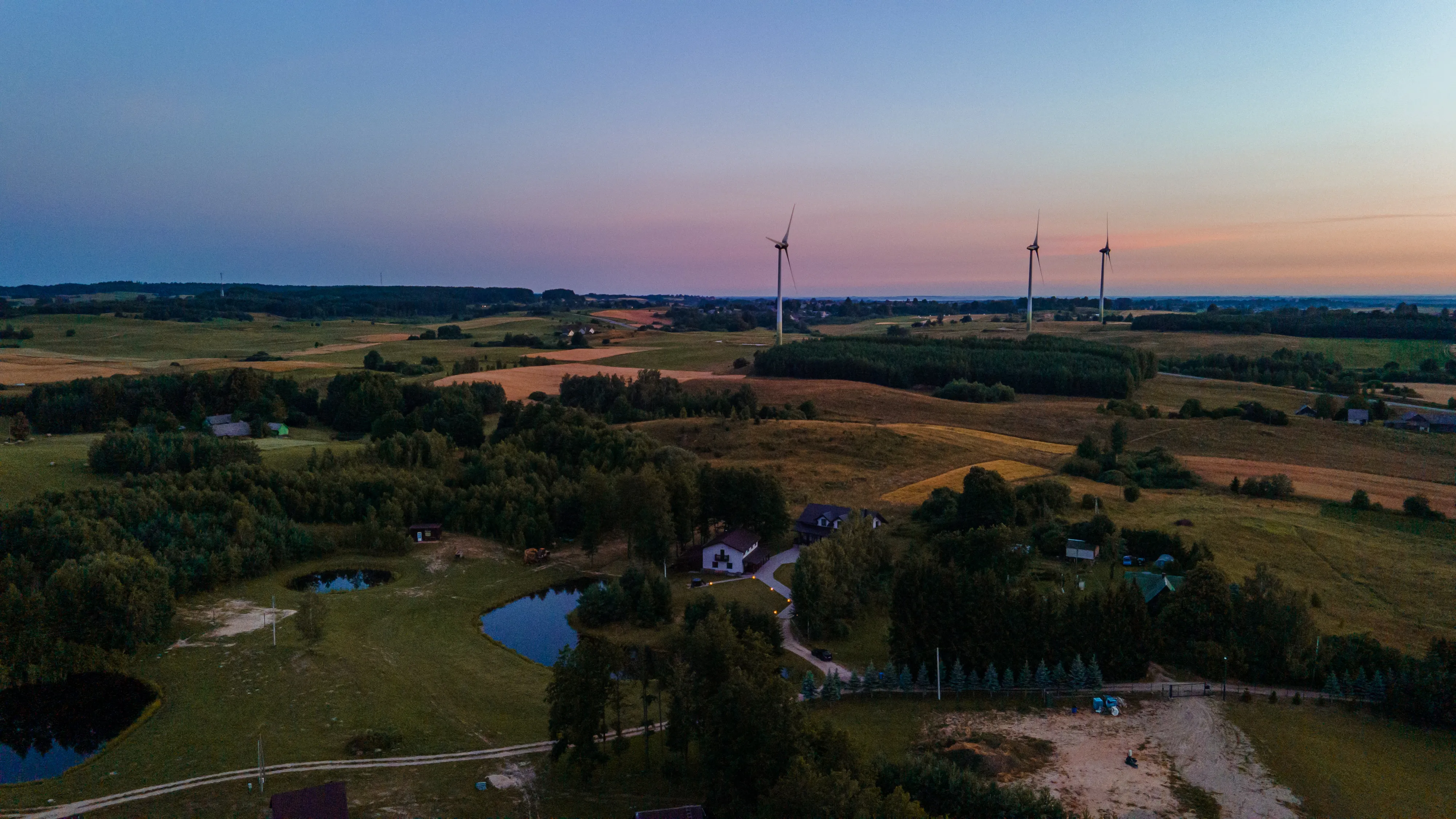 Oro vaizdas į stovylą — sporto aikštynai, miškas, ežeras horizonte, saulėtas oras