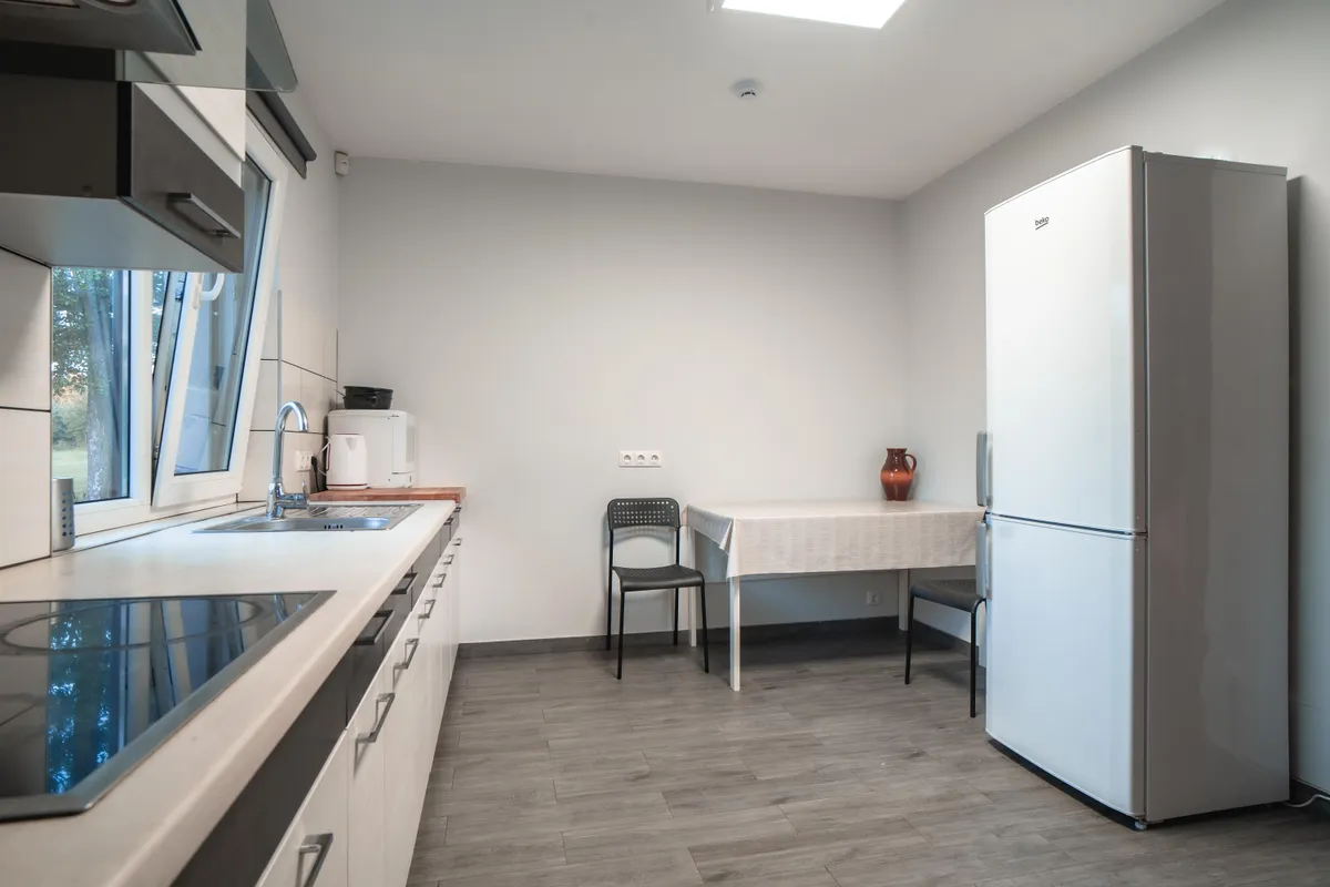 Vilos virtuvė — moderni įranga, didelė darbo plokštė, natūralus švieta